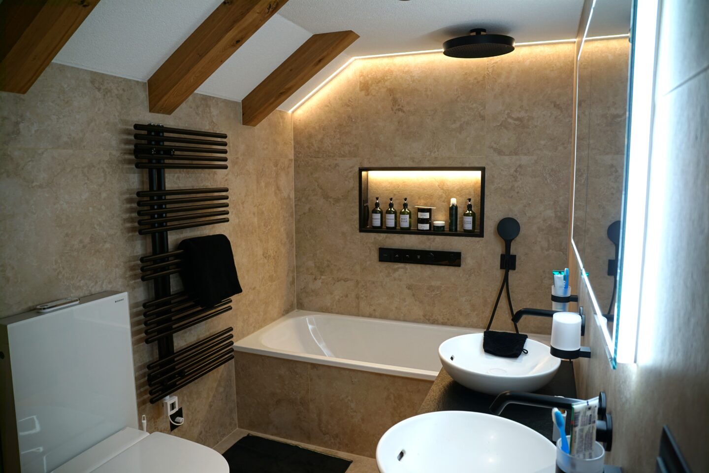 Umgebautes Bad in Ebnat-Kappel mit indirekter Beleuchtung, schrägem Dach, Badewanne und zwei Waschbecken